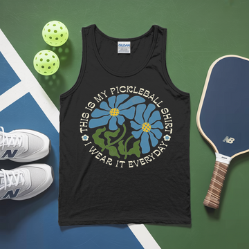 Black tank top with pickleball design on a green and blue surface with pickleballs and a paddle.