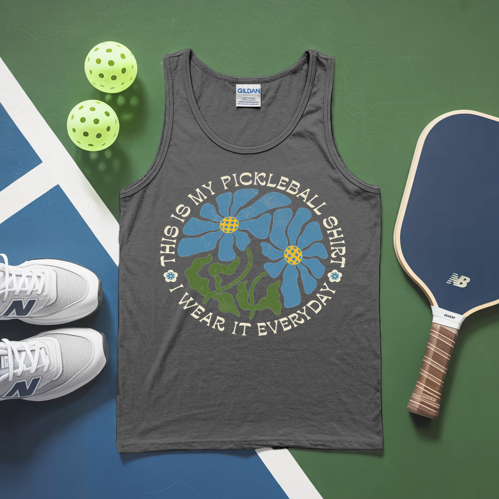 Gray tank top with pickleball-themed design, pickleballs, and paddle on a green and blue surface.