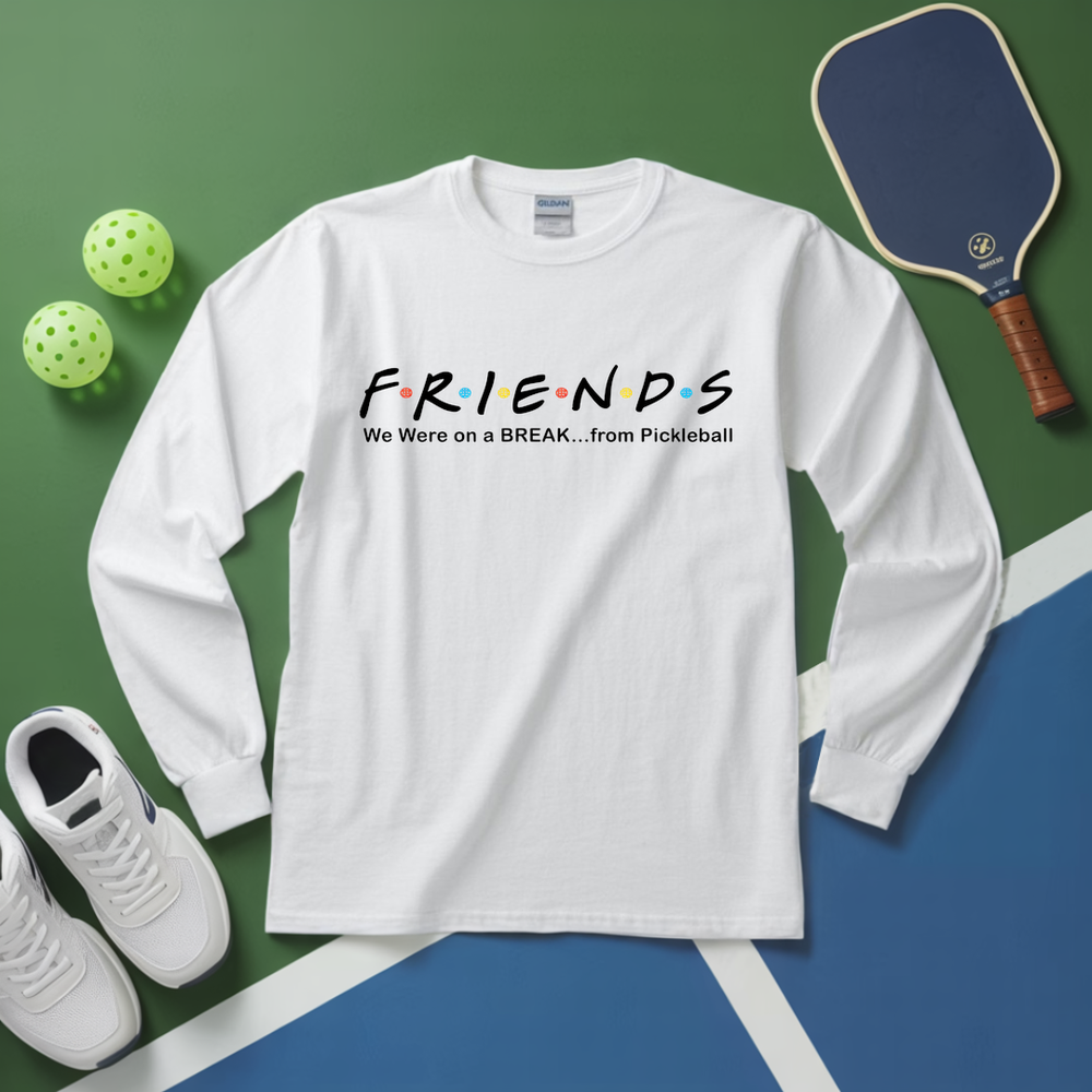 White long-sleeve shirt with 'FRIENDS' design, pickleball paddle, balls, and shoes on a green and blue surface.