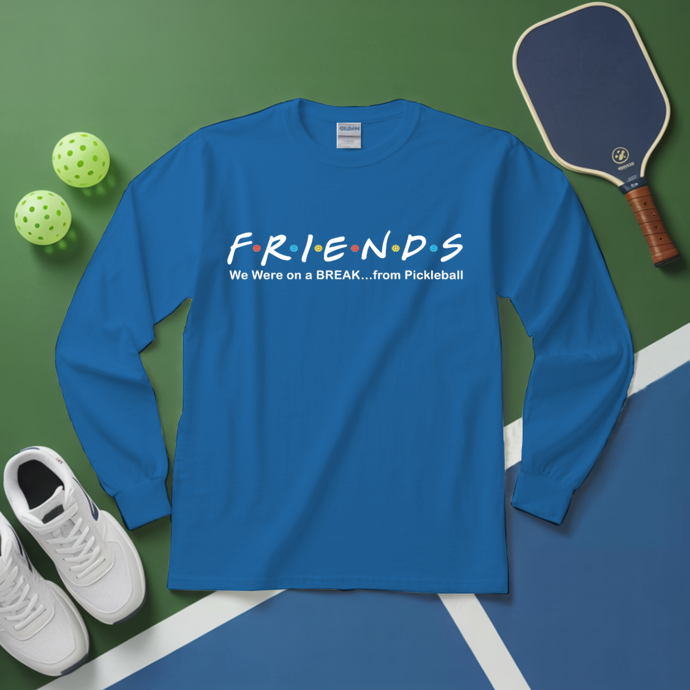 Blue long-sleeve shirt with 'FRIENDS' design on a green surface with pickleball equipment.