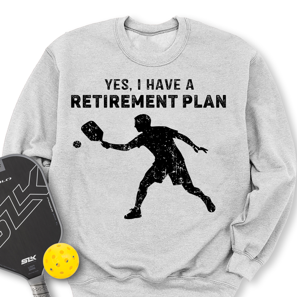 Gray sweatshirt with pickleball design and text 'Yes, I have a retirement plan' on a white background.