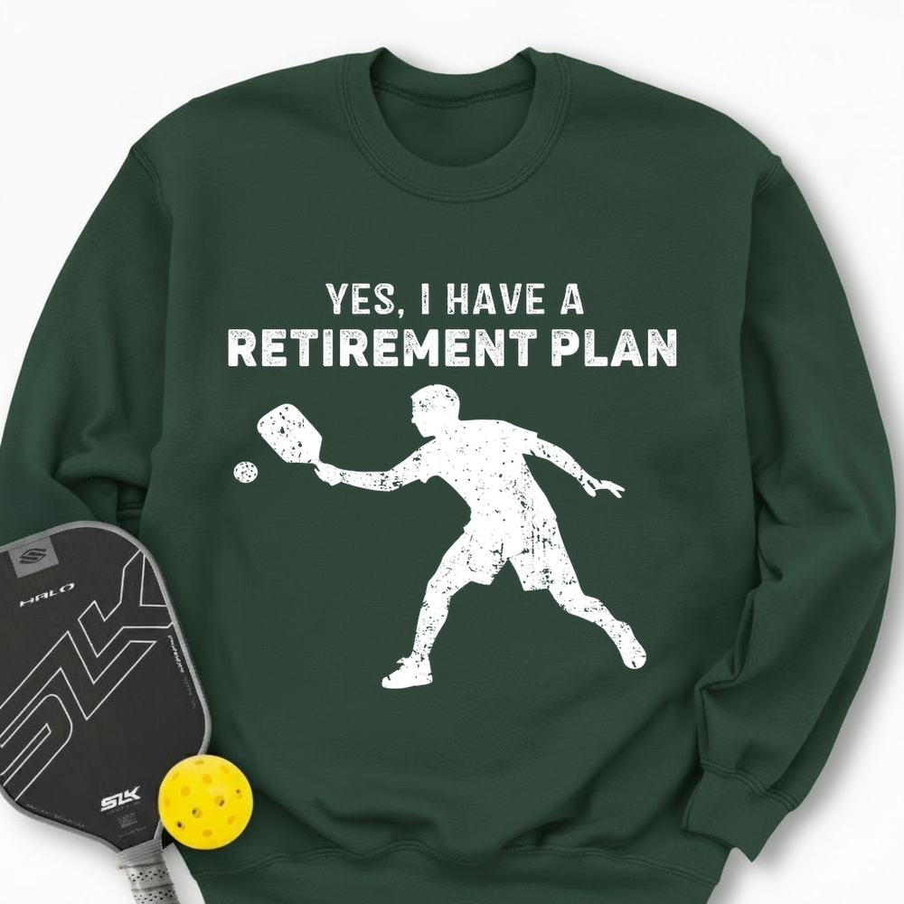 Green sweatshirt with 'YES, I HAVE A RETIREMENT PLAN' text and pickleball player graphic, accompanied by a pickleball paddle and ball.