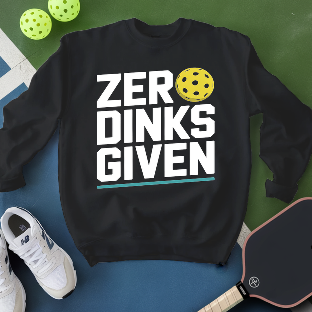 Black sweatshirt with 'ZER DINKS GIVEN' text and pickleball ball, surrounded by pickleballs and paddle on a green and blue background.