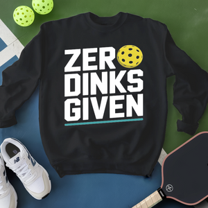 Black sweatshirt with 'ZER DINKS GIVEN' text and pickleball ball, surrounded by pickleballs and paddle on a green and blue background.
