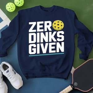 Navy sweatshirt with 'ZER DINKS GIVEN' text and pickleball ball, surrounded by pickleballs and a paddle on a green and blue background.
