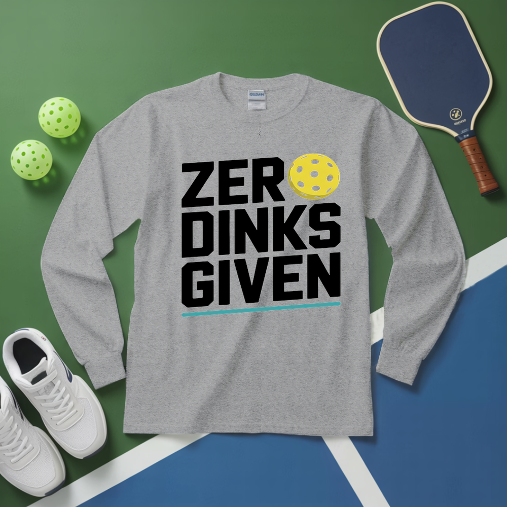 Gray long-sleeve shirt with 'ZER DINKS GIVEN' text, pickleball paddle, balls, and shoes on a green and blue surface.
