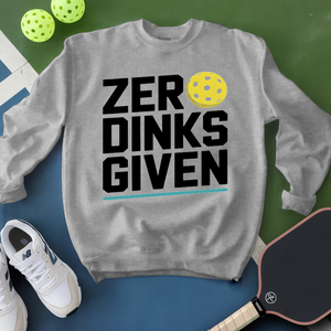 Gray sweatshirt with 'ZER DINKS GIVEN' text, pickleball balls, paddle, and shoes on a green and blue background