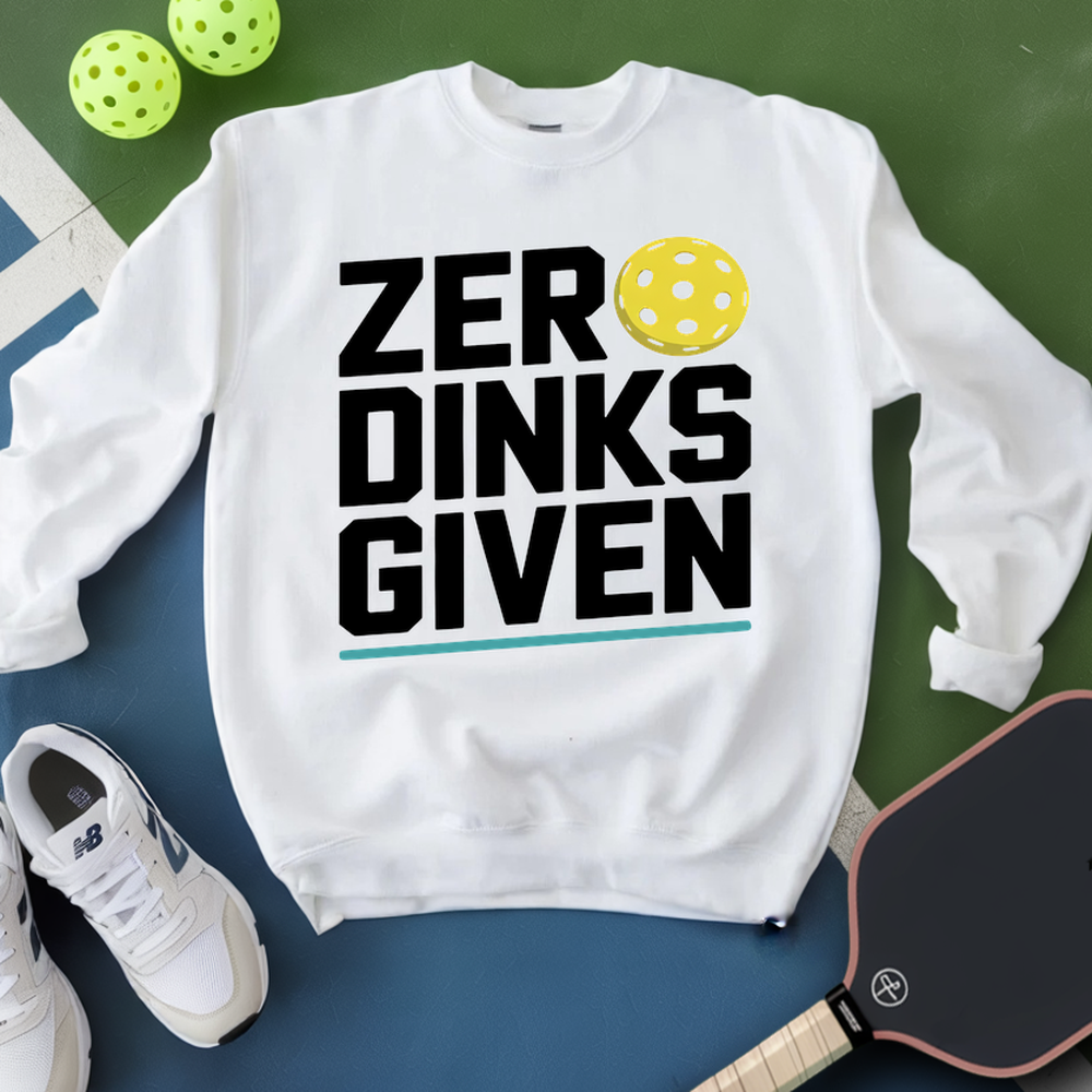 White sweatshirt with 'ZER DINKS GIVEN' text and pickleball elements on a green and blue background.