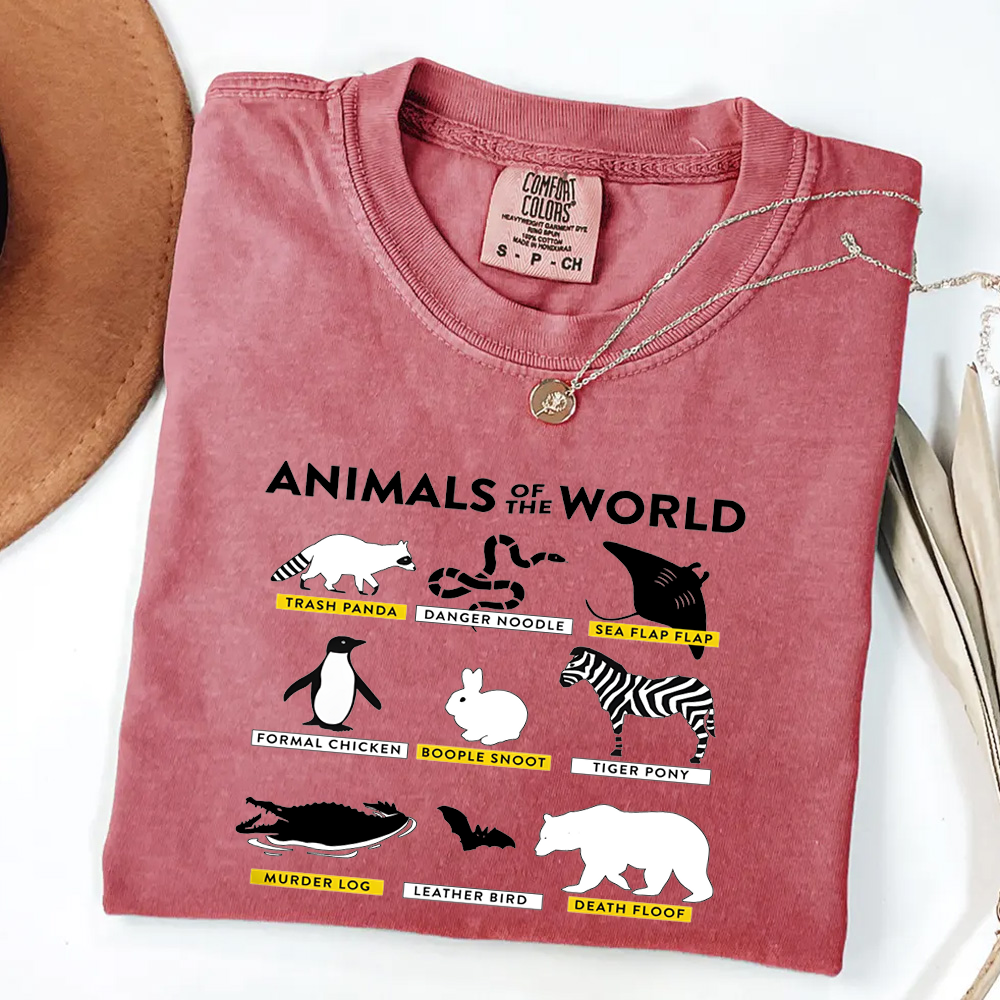 Folded pink t-shirt with 'Animals of the World' graphic on a white surface.