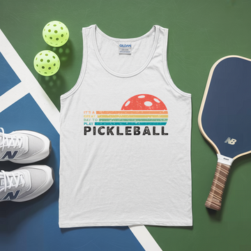 White tank top with pickleball design, pickleballs, and paddle on a green and blue surface