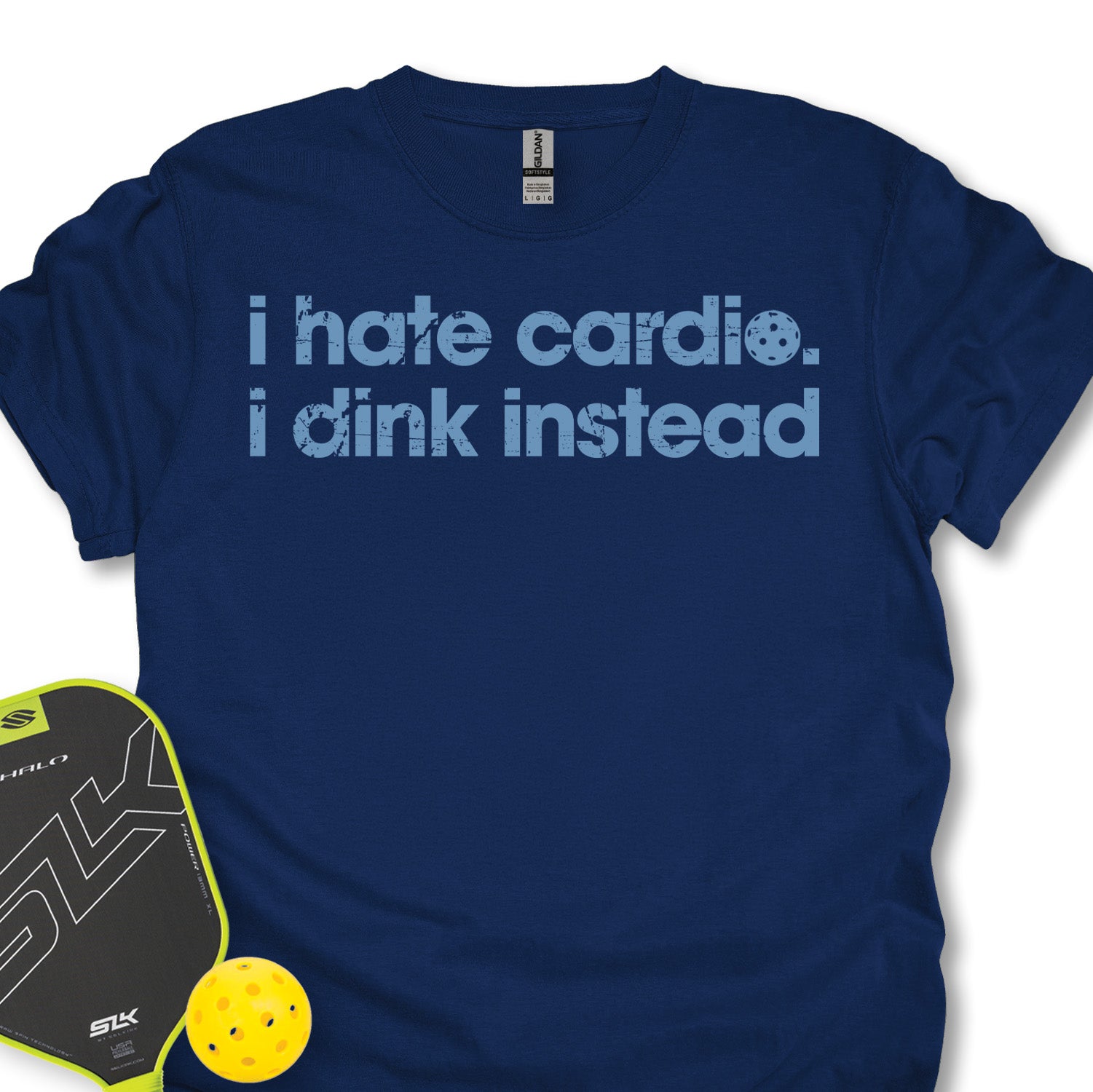 Navy blue t-shirt with 'i hate cardio. i dink instead' text, next to a pickleball paddle and ball on a white background