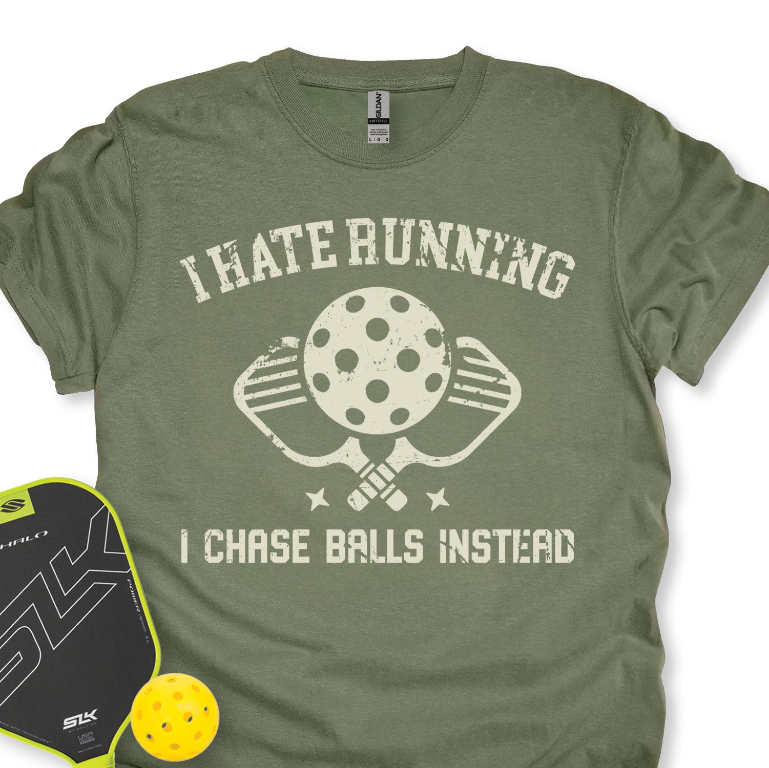 Green t-shirt with pickleball-themed design and accessories on a white background