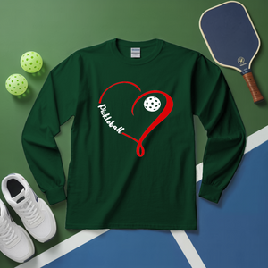 Green long-sleeve shirt with red heart design and pickleball text, placed on a green and blue surface with pickleball equipment.