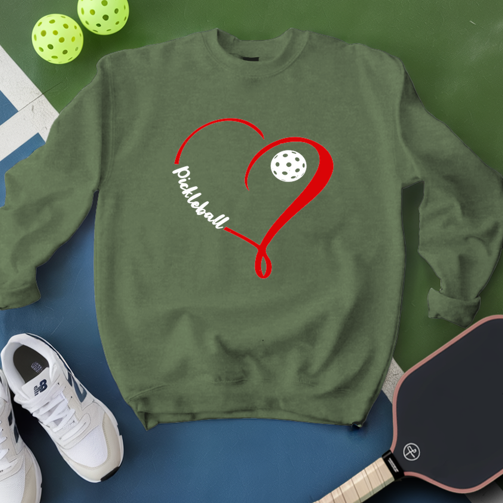 Green sweatshirt with red heart and pickleball design, surrounded by pickleballs and a paddle on a green and blue background.