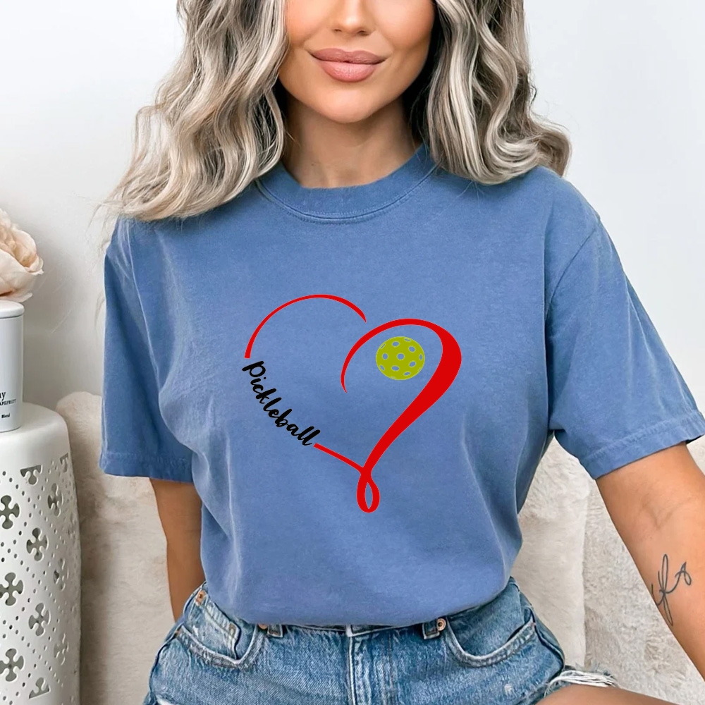 Person wearing a blue t-shirt with a red heart and yellow ball design, sitting on a couch.