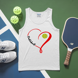 White tank top with pickleball design, pickleballs, and paddle on a green and blue surface
