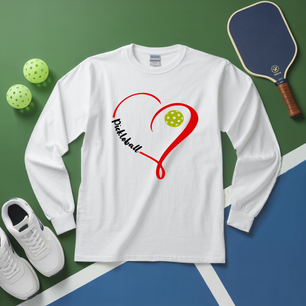 White long-sleeve shirt with pickleball design on a green and blue surface with pickleballs and a paddle.