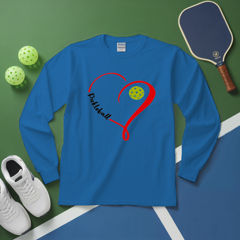 Blue long-sleeve shirt with pickleball design on a green and blue surface with pickleballs and a paddle.