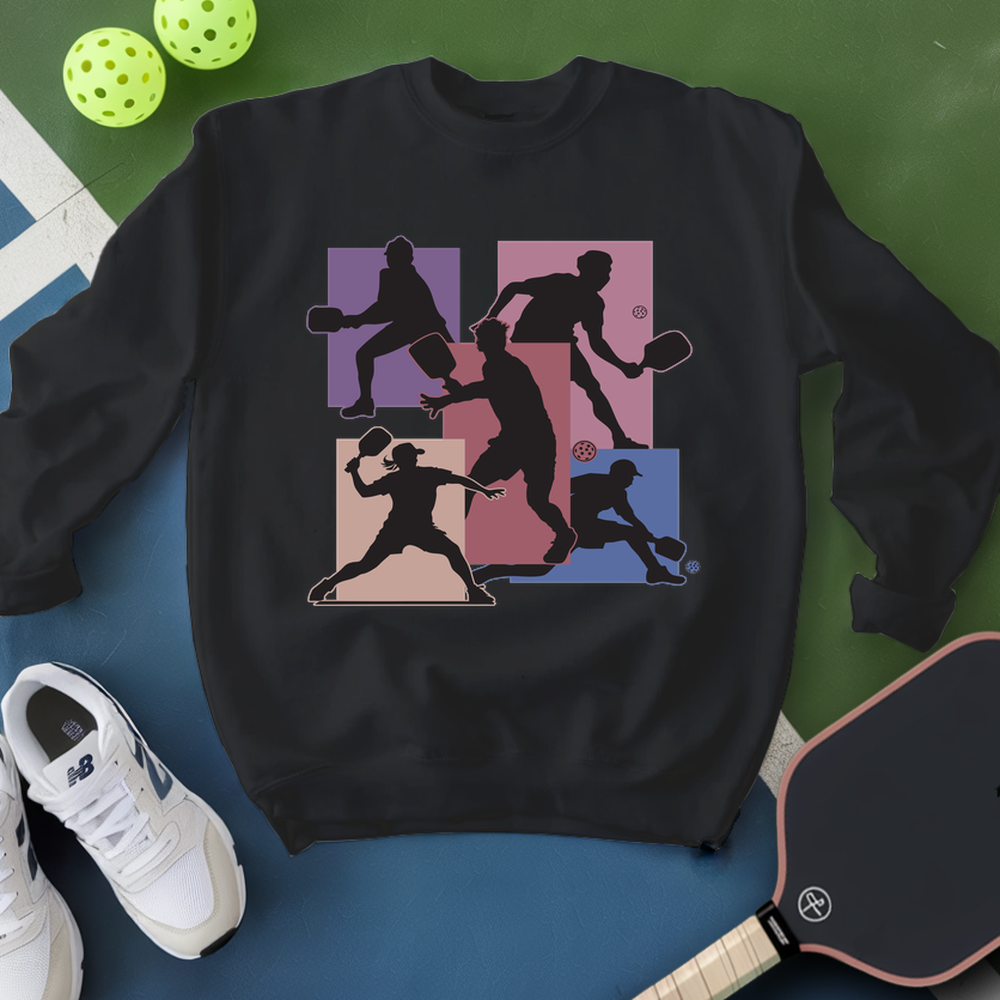 Black sweatshirt with pickleball player design, white sneakers, and paddle on a green and blue background