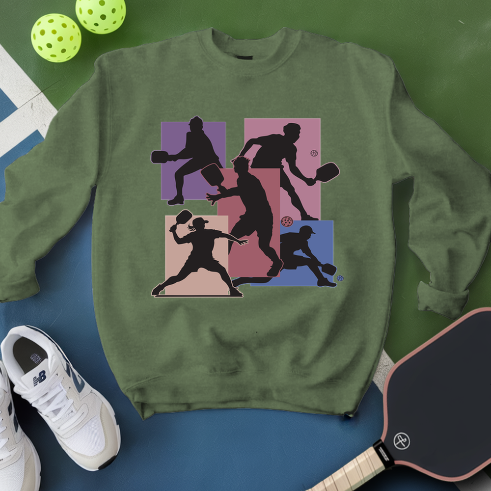 Green sweatshirt with pickleball player design, surrounded by pickleballs and a paddle on a green and blue background.