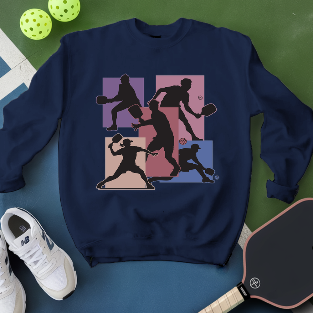 Navy blue sweatshirt with pickleball player graphic on a green and blue surface with pickleballs and paddle.