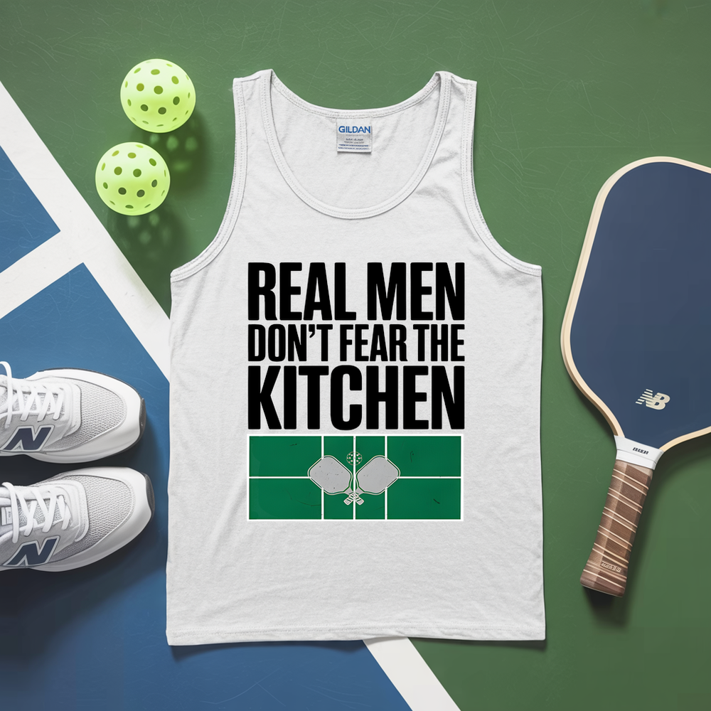White tank top with 'Real Men Don't Fear The Kitchen' text, pickleball paddles, balls, and shoes on a green and blue background.