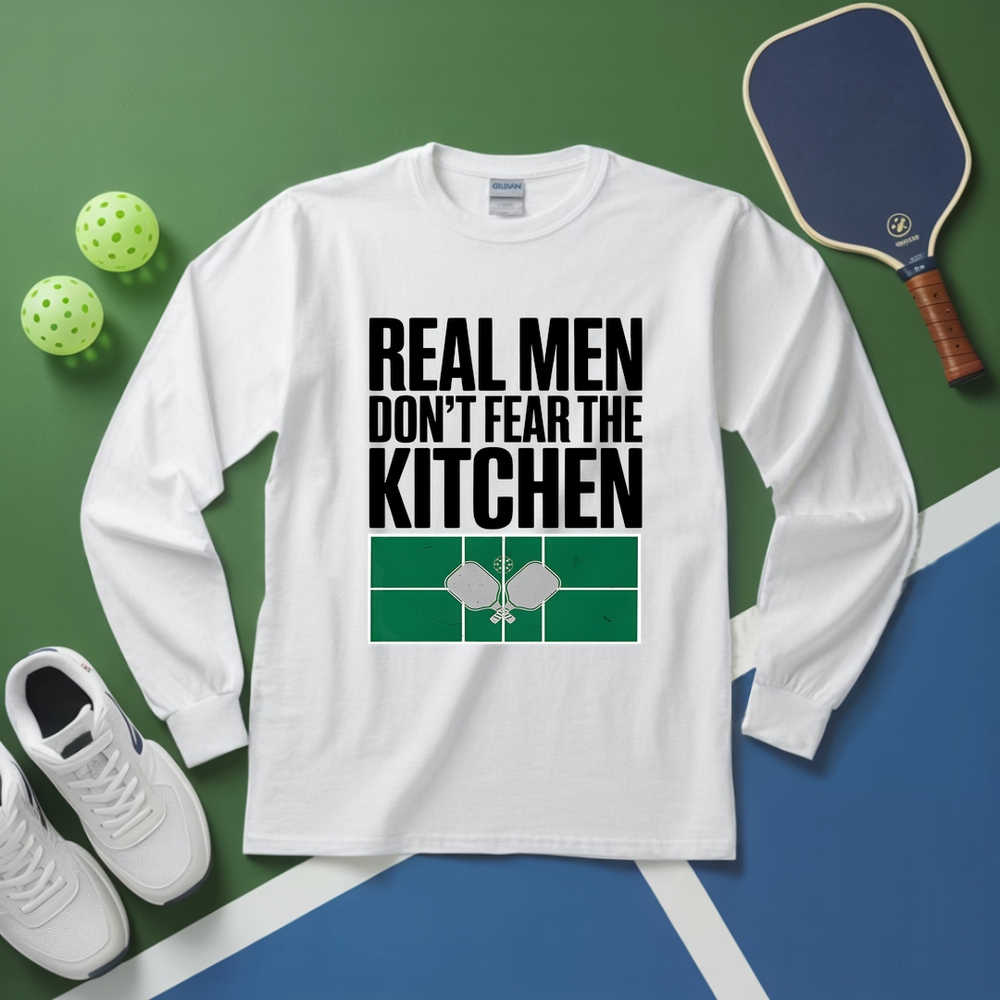 White long-sleeve shirt with 'Real men don't fear the kitchen' text on a green and blue background with pickleball equipment.