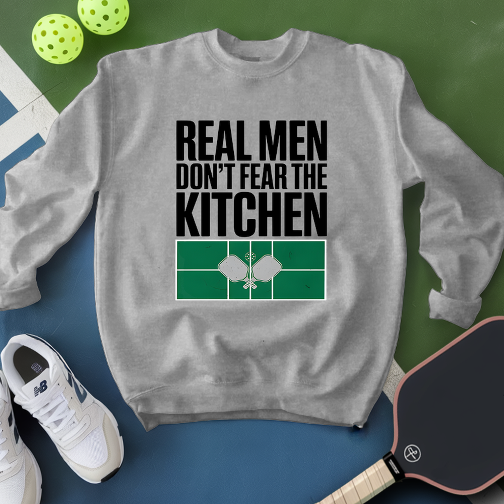 Gray sweatshirt with 'Real Men Don't Fear The Kitchen' text and pickleball equipment on a green and blue background